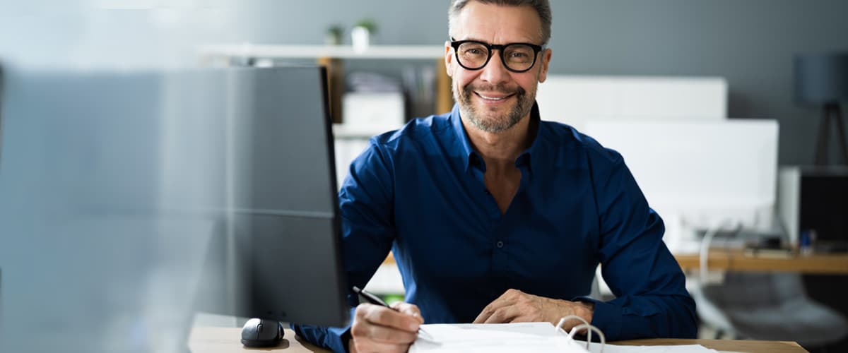 Man achter computer met papieren