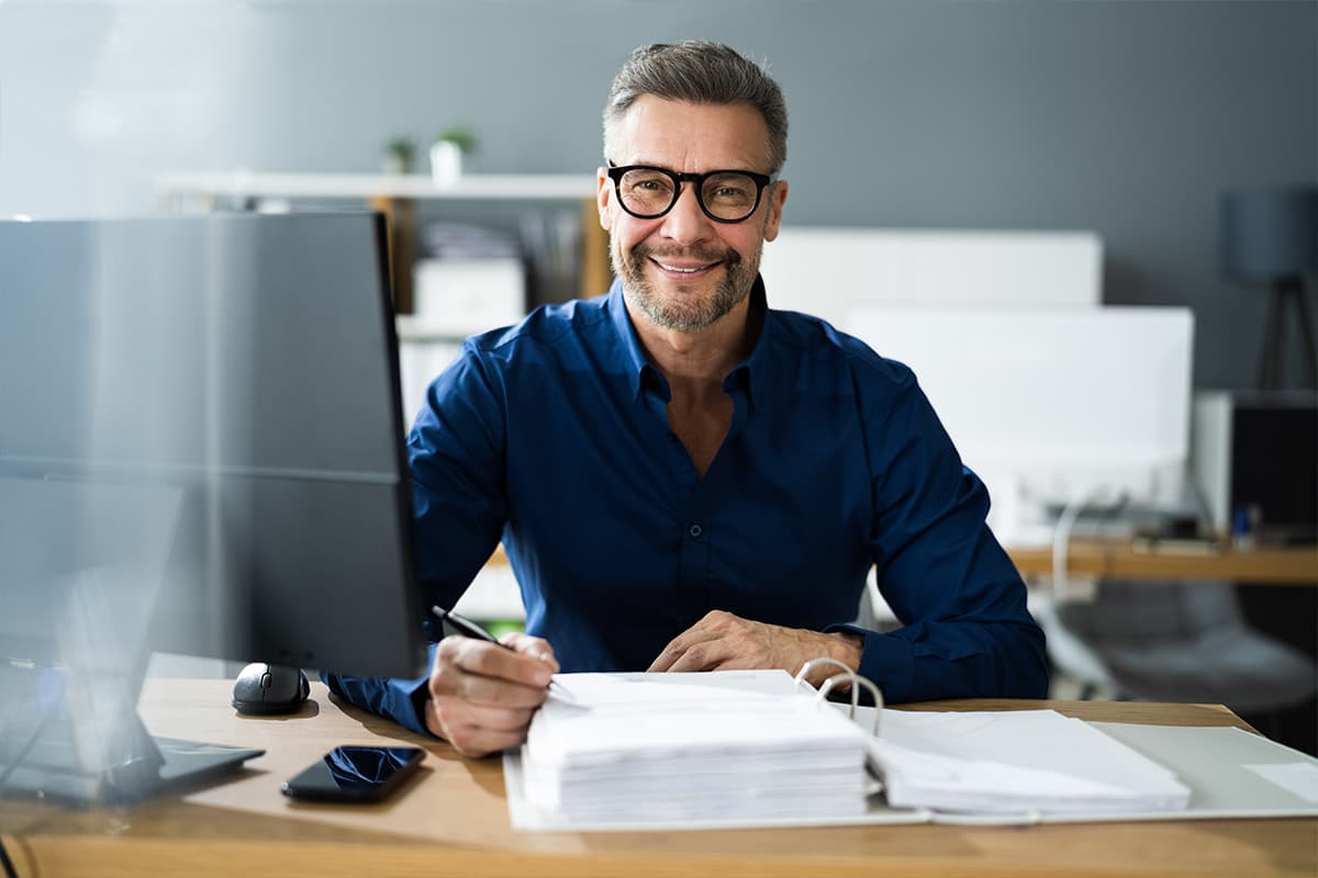 Man achter computer met papieren