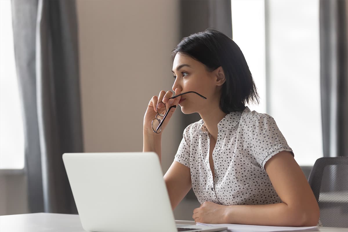 Vrouw peinzend achter laptop